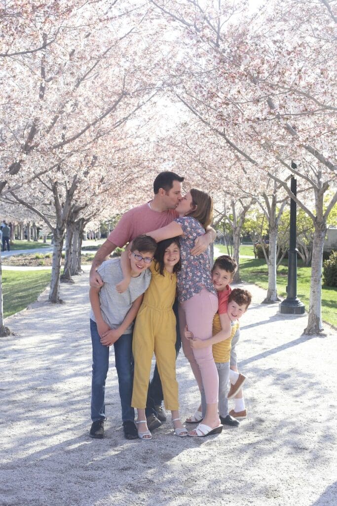 A family enjoying springtime under blooming cherry blossom trees on a paved path near the Utah State Capitol.