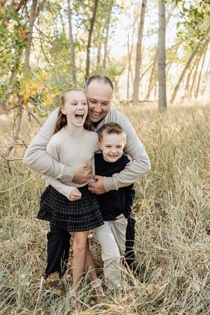 Dad happily surprises his two children with a big bear hug.
