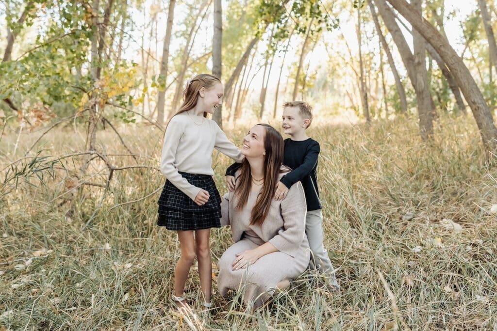 A family laughs together while playing telephone in a field at their family photo session.