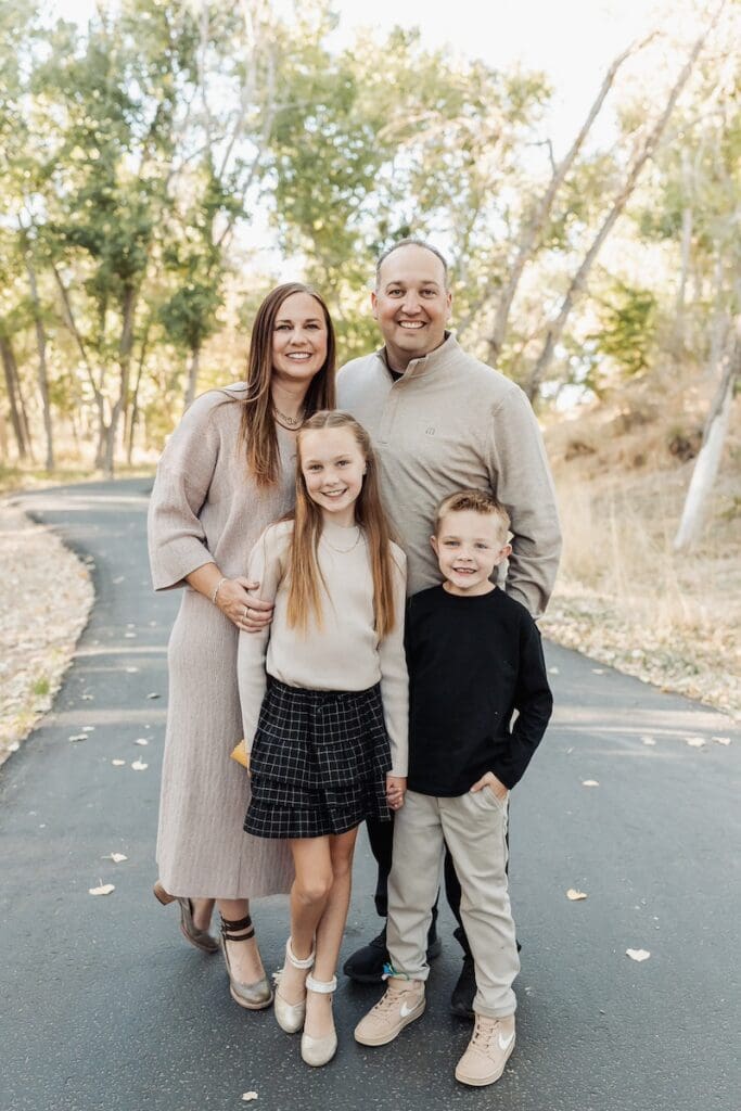 Family standing happily on the jordan river parkway during their utah photo session.